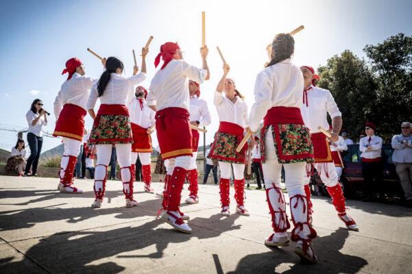 Participants vestits de forma tradcional amb camisa blanca i faixa vermella dansant les Caramelles